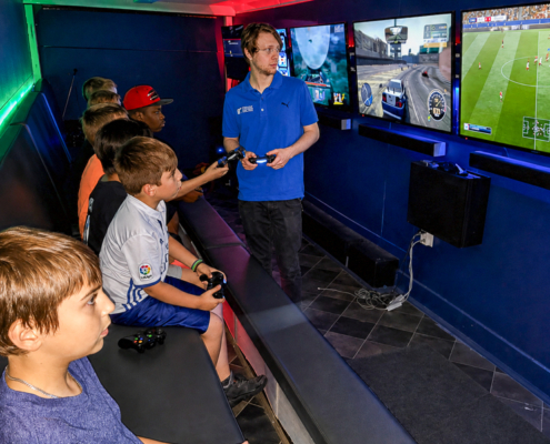 Game Coach helping kids play multiplayer games inside a mobile gaming trailer