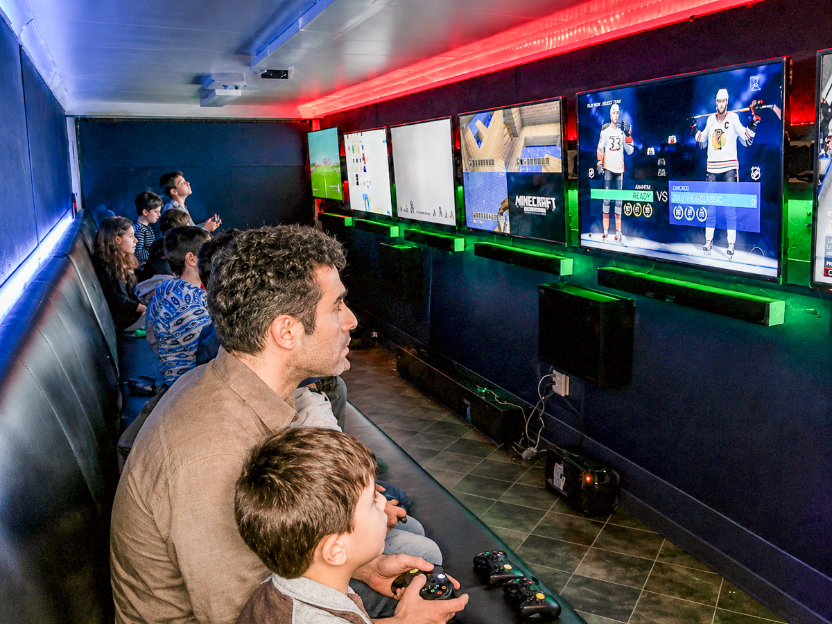 Parent and child playing video games inside the Game Trucks GT trailer