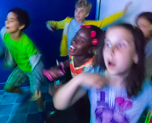 Kids dancing together inside GameTrucks GT gaming trailer
